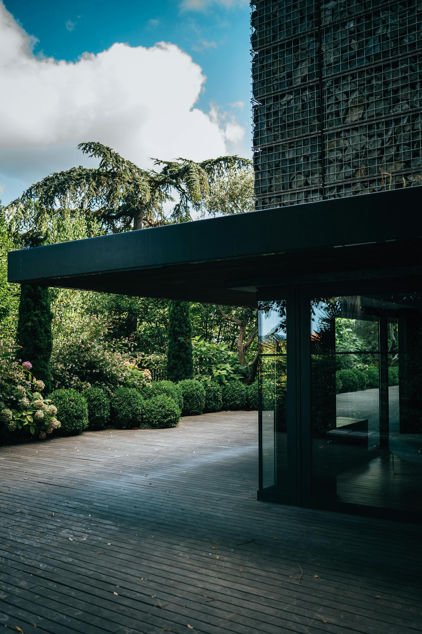 Contemporary building facade surrounded by lush garden and wooden deck.