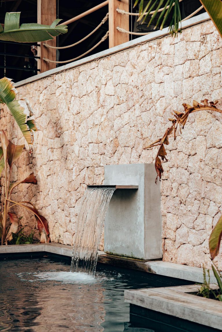 Vertical shot of a contemporary garden with water fountain and tropical plants.